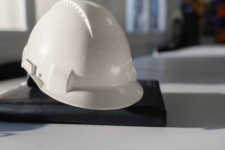 White hard hat and safety equipment on desk, construction site office still life